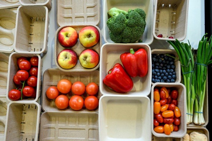 Desde arriba se puede ver una selección de envases de cartón de diversas formas y tamaños, llenos de diferentes tipos de frutas y verduras.